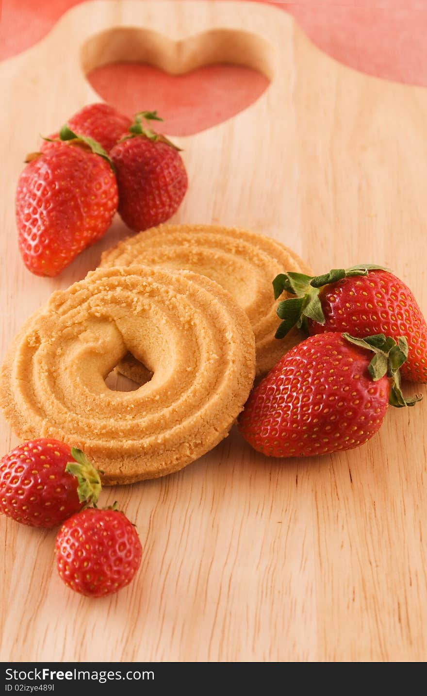 Strawberries with cookies on wooden board