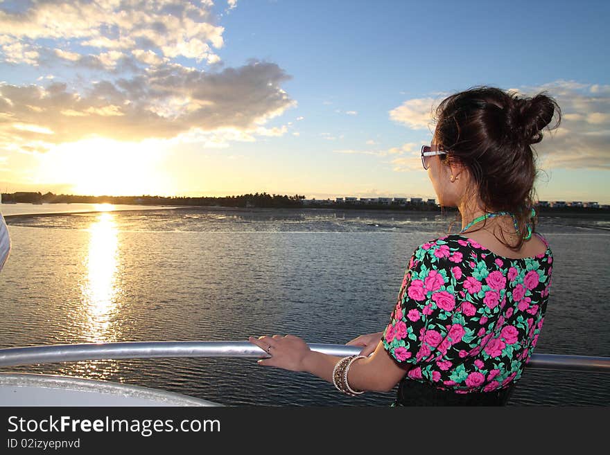 An Asian girl is appreciating the charming sunset on a yacht. An Asian girl is appreciating the charming sunset on a yacht.