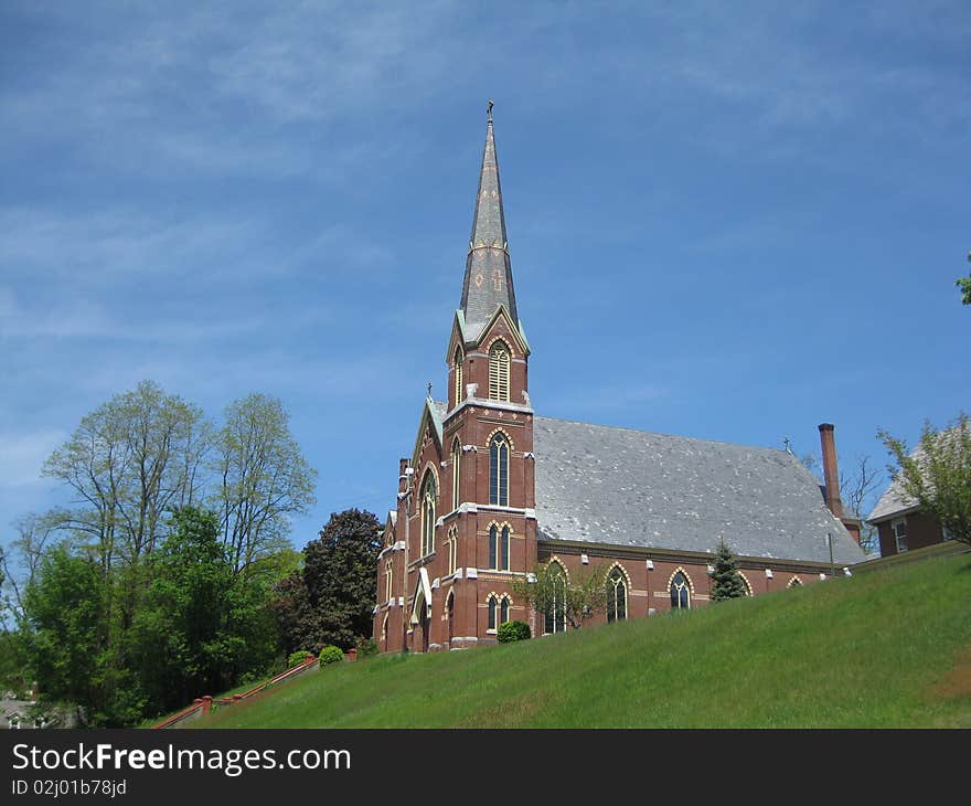 A beautiful Catholic Church sits high on a hill in Vermont against the deep blue sky. A beautiful Catholic Church sits high on a hill in Vermont against the deep blue sky