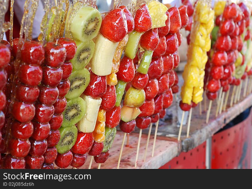 This image is of fruits on a stick. They are soaked in a sweet candy. The candy then hardens into a shell covering the fruit. Very sweet tasting. This image is of fruits on a stick. They are soaked in a sweet candy. The candy then hardens into a shell covering the fruit. Very sweet tasting.