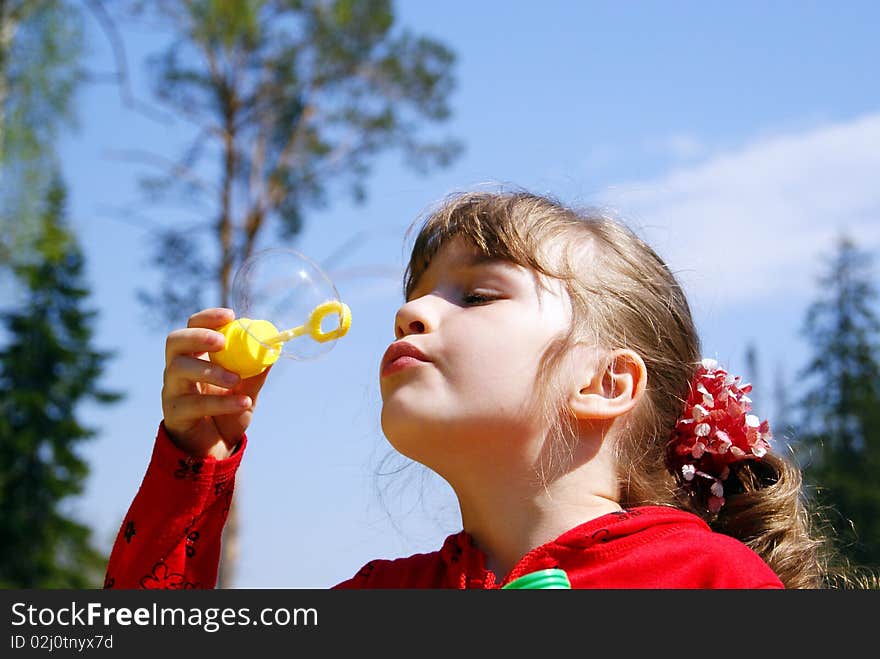 In the summer on the nature the girl inflates a soap bubble. In the summer on the nature the girl inflates a soap bubble