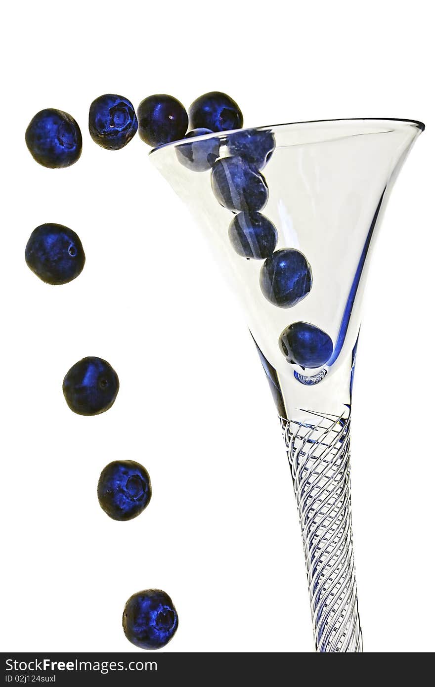 Fresh blueberries appear to be popping out of a crystal cocktail glass on an isolated white background. Fresh blueberries appear to be popping out of a crystal cocktail glass on an isolated white background