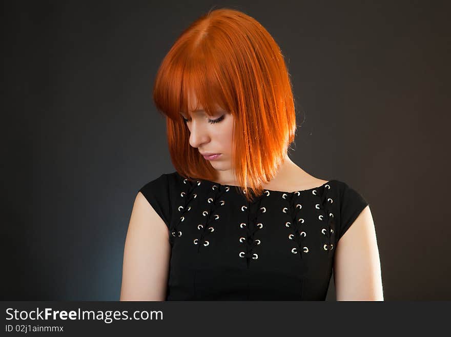 Beautiful red girl in an evening dress against a dark background. Beautiful red girl in an evening dress against a dark background