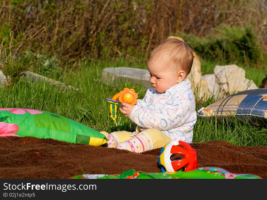 The little girl playing with rattles on a lawn. The little girl playing with rattles on a lawn