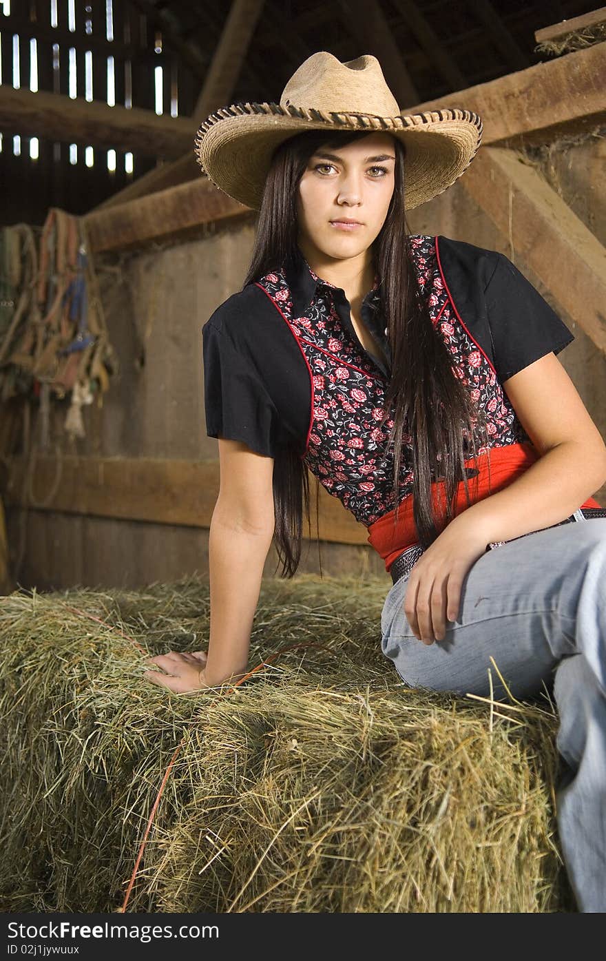 Cowgirl posing on hay with vest and hat. Cowgirl posing on hay with vest and hat