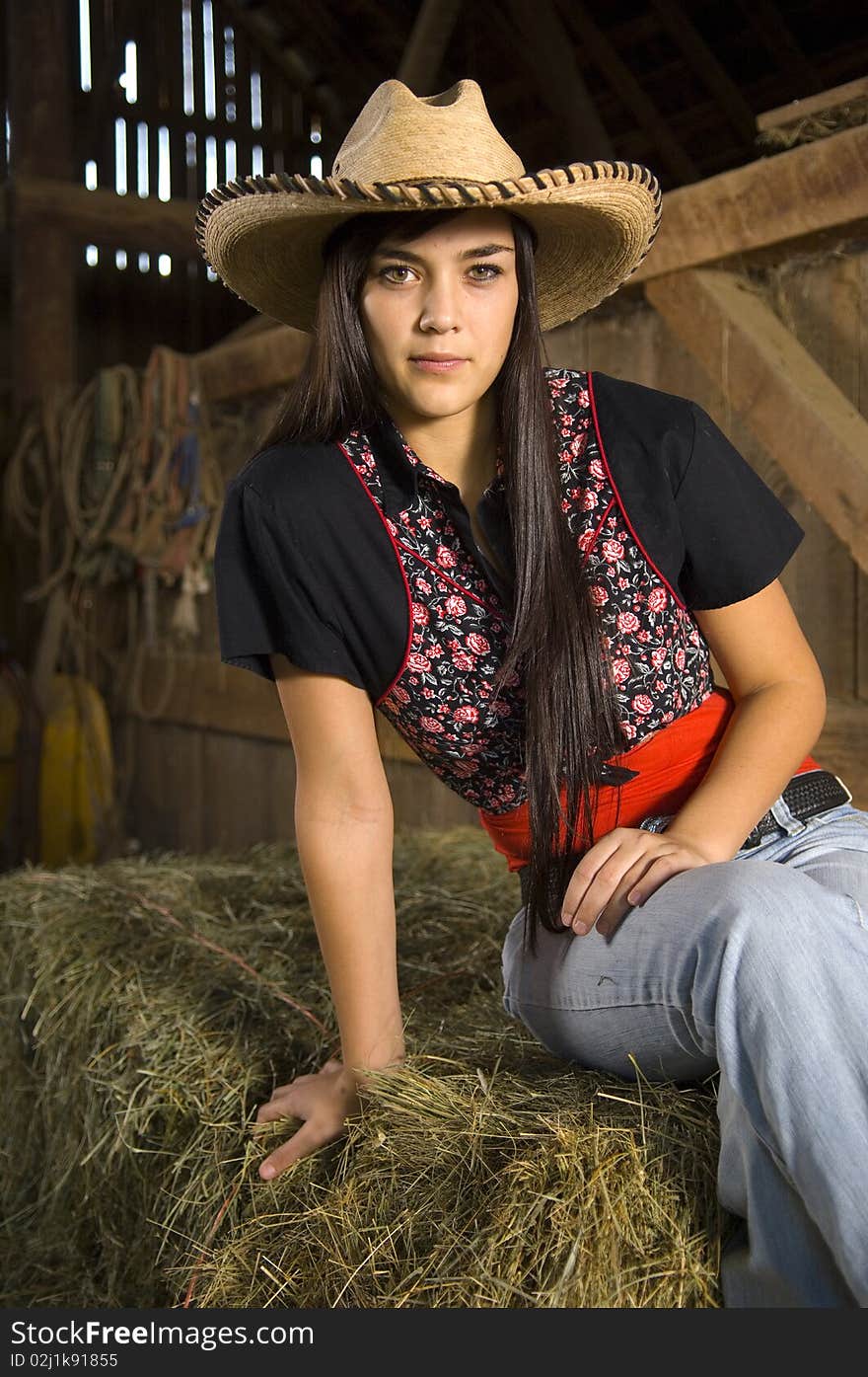 Cowgirl posing on hay with vest and hat. Cowgirl posing on hay with vest and hat