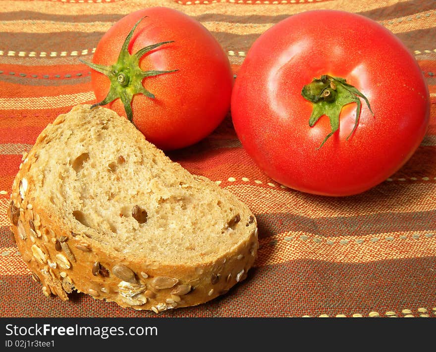 A piece of bread with tomatoes on a striped tablecloth