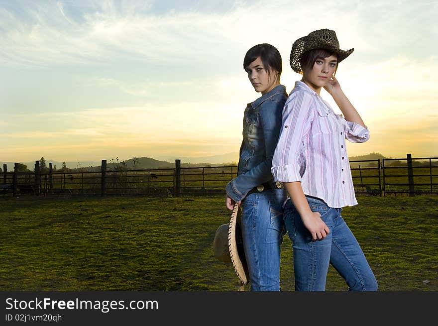 Twin cowgirls in a coral against a fall sunset