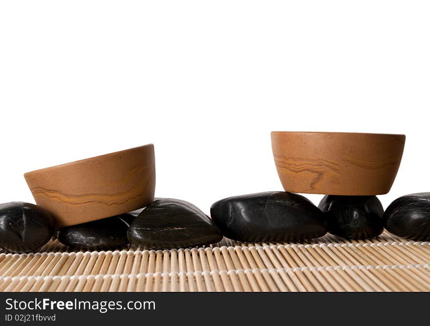 Two clay cups, mat and stones isolated in white