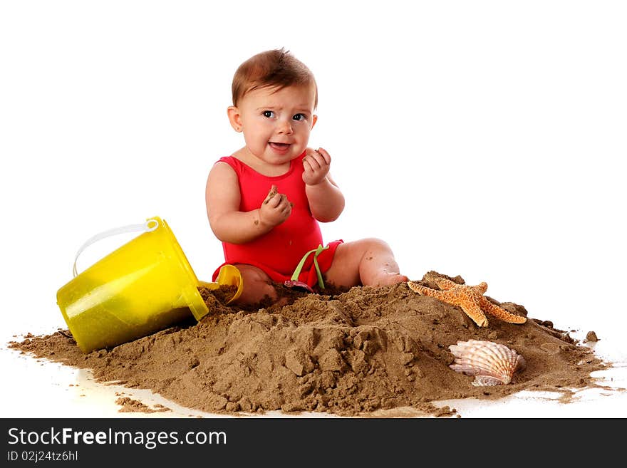 A baby girl with sand toys and shells making faces after tasting the sand she's sitting in. Isolated on white. A baby girl with sand toys and shells making faces after tasting the sand she's sitting in. Isolated on white.