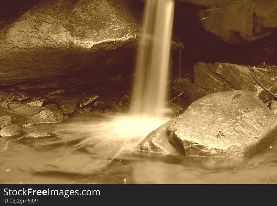 A small waterfall landing on rocks. A small waterfall landing on rocks