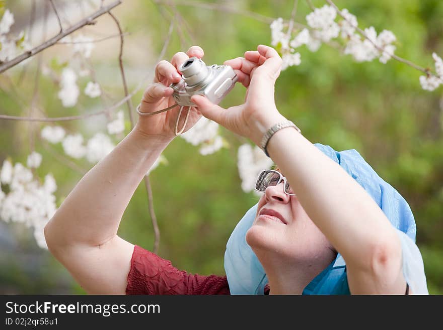 Beautiful senior woman taking photos outdoors in spring garden