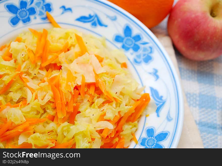 Asian healthy stir fried vegetables cooked with cabbage and carrots with fruits in background. For concepts such as food and beverage, diet and nutrition, and healthy eating. Asian healthy stir fried vegetables cooked with cabbage and carrots with fruits in background. For concepts such as food and beverage, diet and nutrition, and healthy eating.