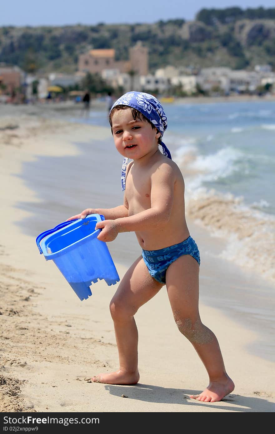 Child of the sea that plays with the blue bucket. Child of the sea that plays with the blue bucket