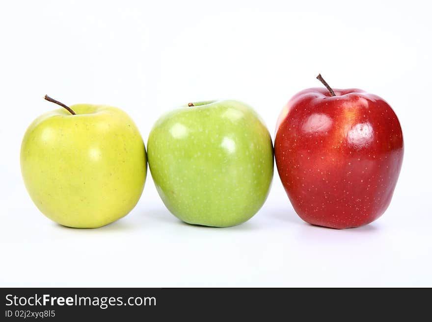 Three apples (green, yellow,red) in a raw on white background