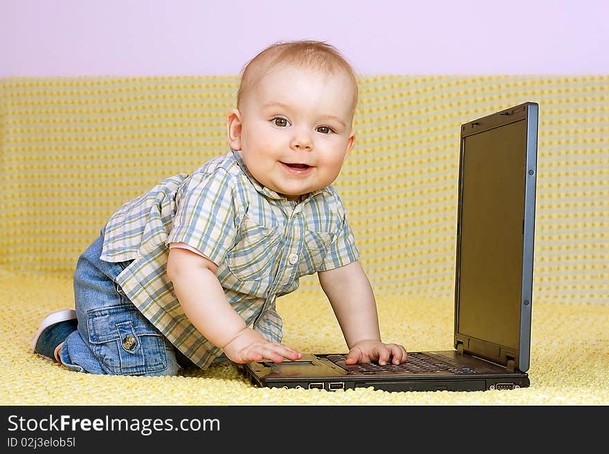 Kid plays with laptop on yelow background