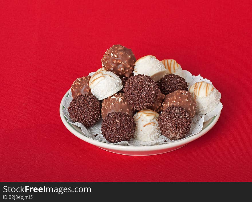 Plate of assorted chocolate bon bon on a red table cloth. Plate of assorted chocolate bon bon on a red table cloth