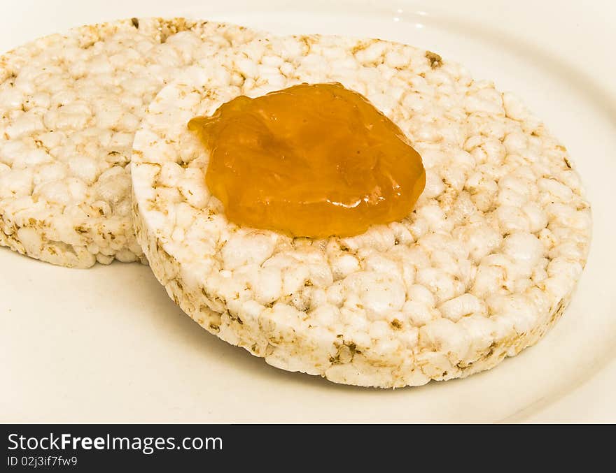 Rice biscuits with apricot jam on a white plate background