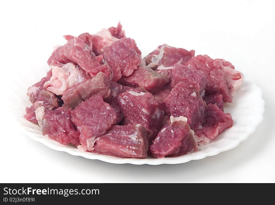 Small pieces of raw meat on white plate, chopped on little blocks. isolated on white background. Small pieces of raw meat on white plate, chopped on little blocks. isolated on white background.