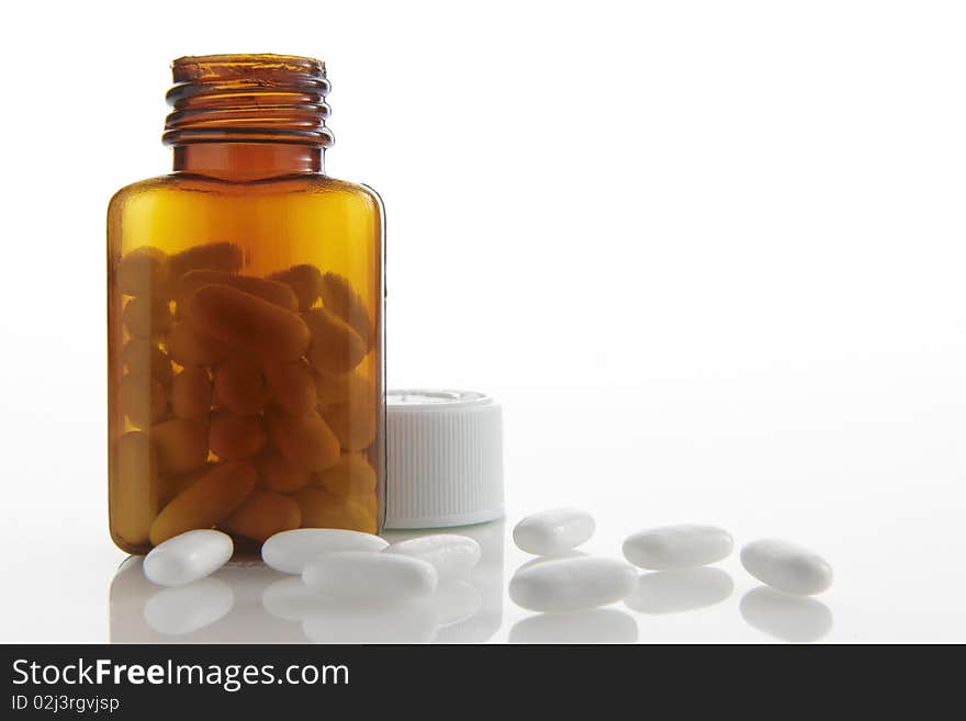 Pills lying on white background next to bottle with space for copy. Pills lying on white background next to bottle with space for copy