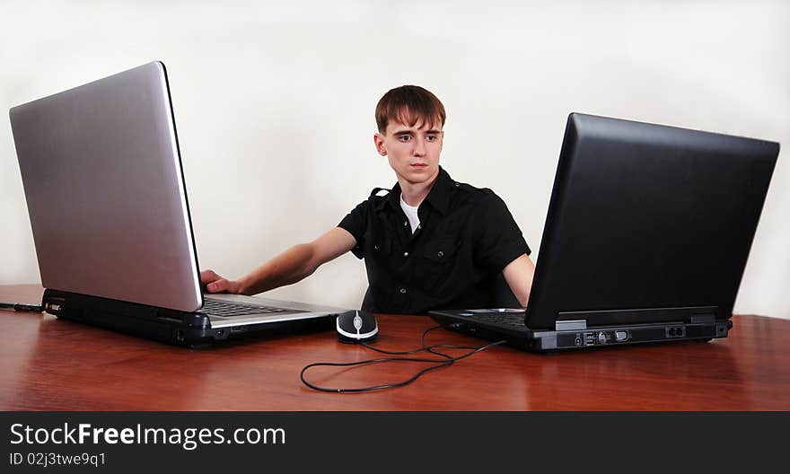 Young guy is operating two laptops at the same time. Young guy is operating two laptops at the same time