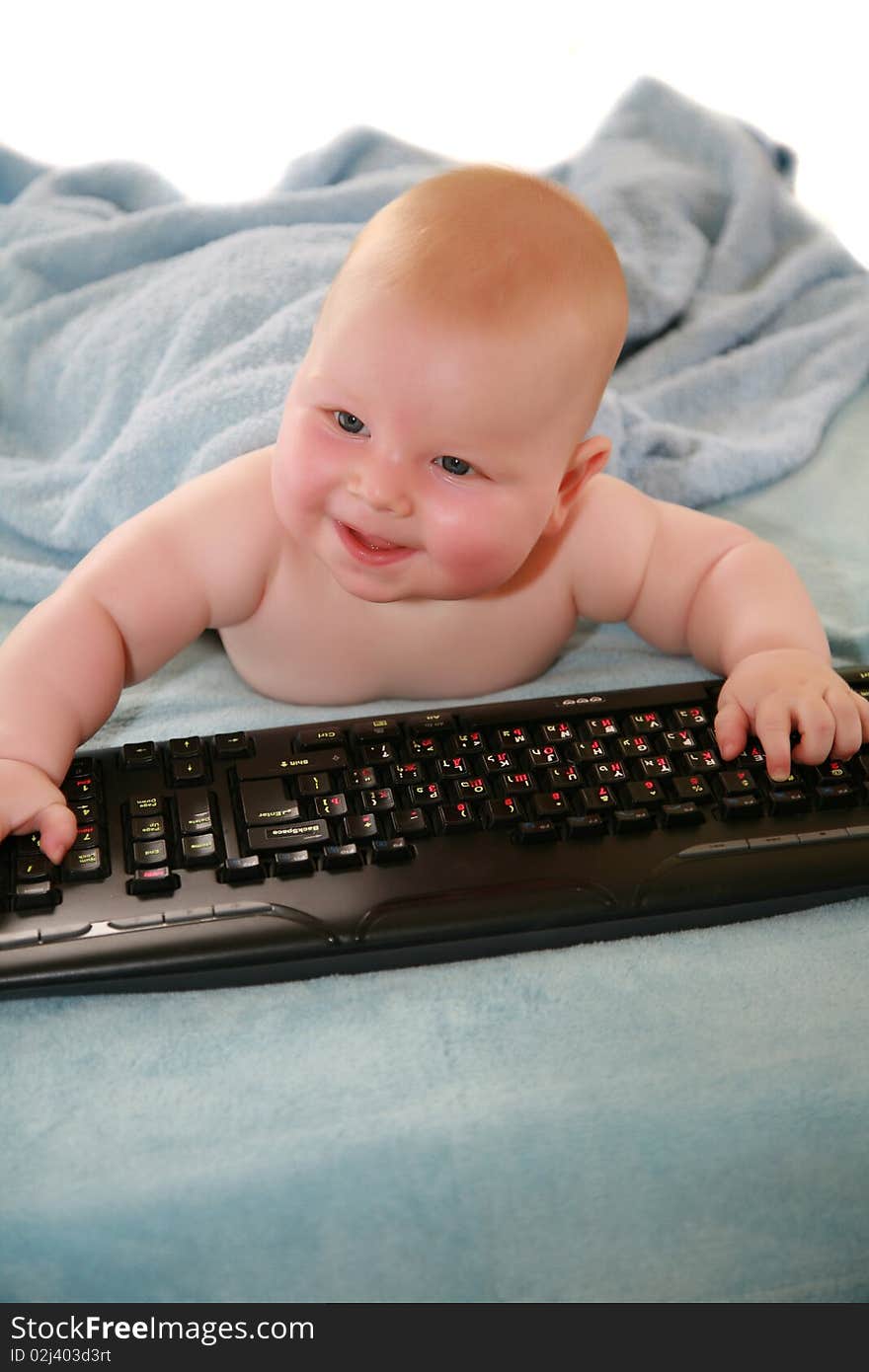 Blonde boy with blue eyes and rosy cheeks, played on a black keyboard and looks at the camera. Blonde boy with blue eyes and rosy cheeks, played on a black keyboard and looks at the camera