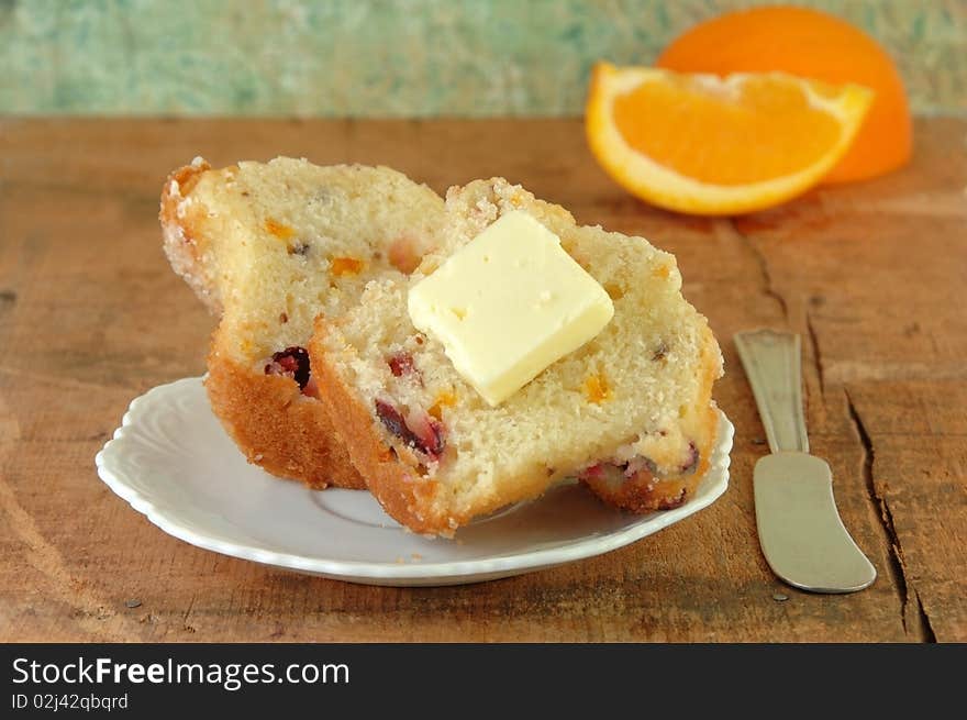 Muffin cut in half with butter. Oranges in the background. Muffin cut in half with butter. Oranges in the background.