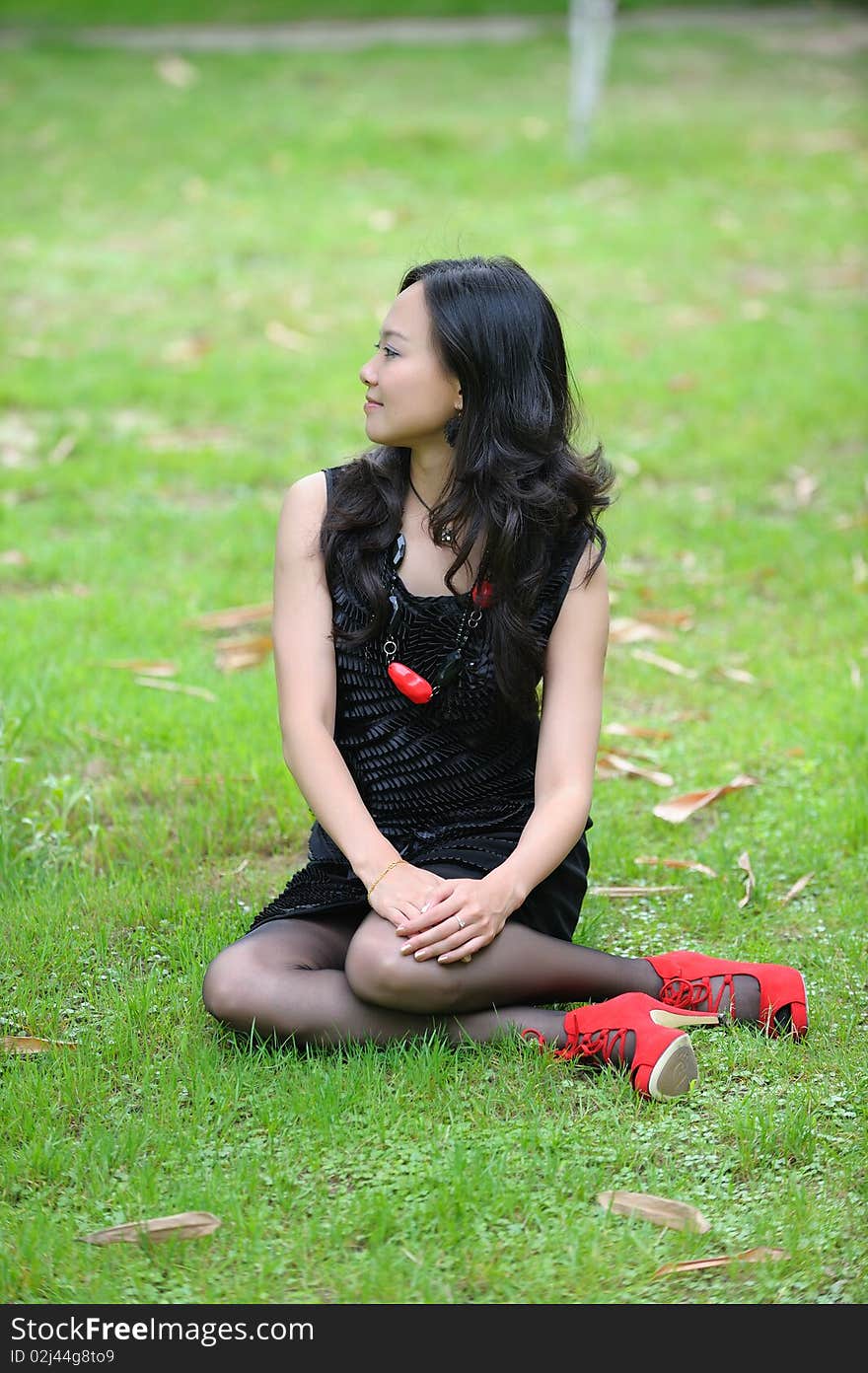 Asian woman sitting on grass.