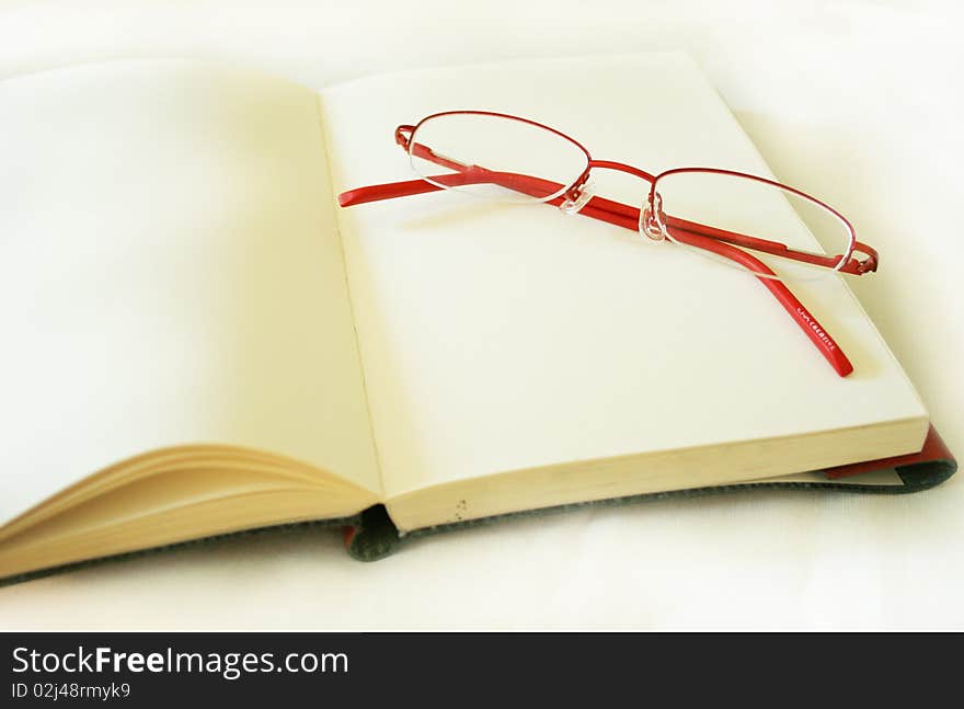 Notebook made of a red skin and glasses