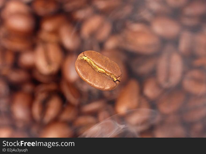 Coffee bean in smoke on the background of coffee beans (selective focus)