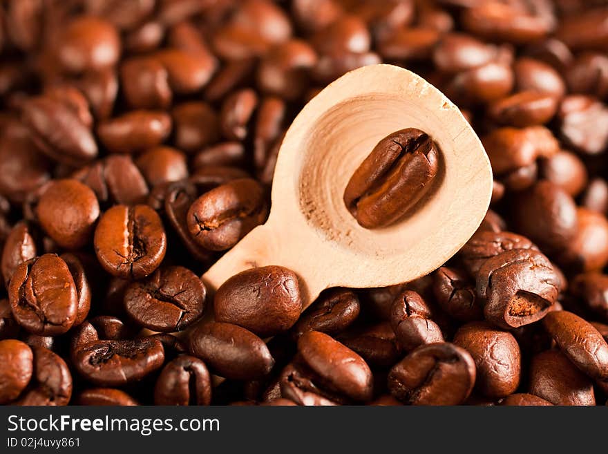 Coffee beans in a spoon, on the background of coffee (selective focus)