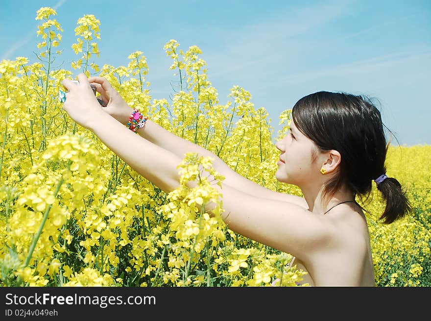 A beautiful girl taking photos of oilseed flowers. A beautiful girl taking photos of oilseed flowers