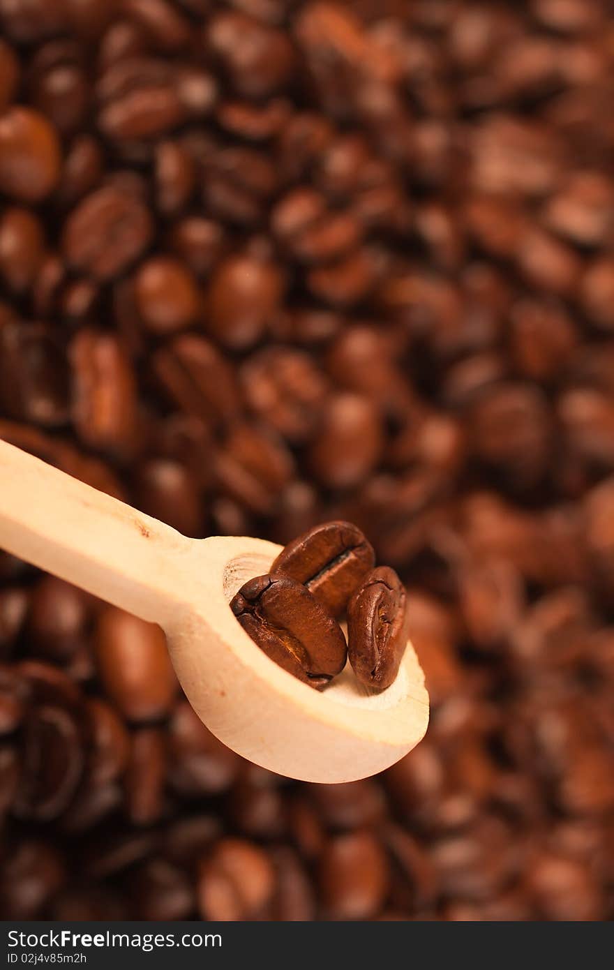 Coffee beans in a spoon, on the background of coffee (selective focus)