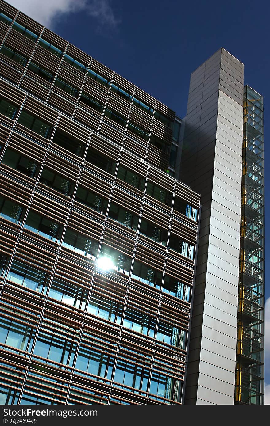 Top of a modern building in Paddington waterside area in London, England. Staircase with a yellow axis is seen through glass windows on the right side. There is a spark of light on one of the windows focusing on this office among the others. Top of a modern building in Paddington waterside area in London, England. Staircase with a yellow axis is seen through glass windows on the right side. There is a spark of light on one of the windows focusing on this office among the others.