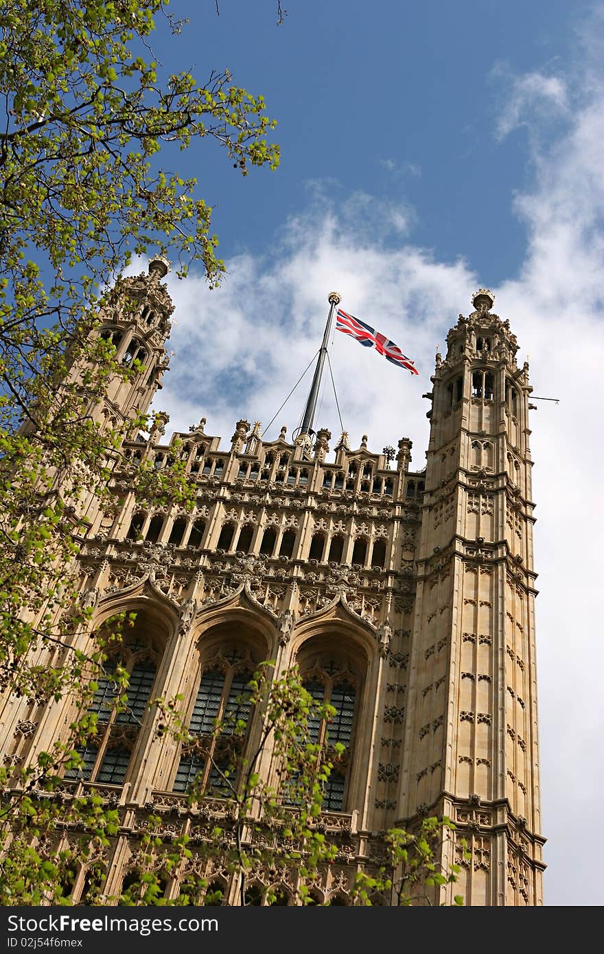 UK Parliament in London viewed from the park along the Thames river with blue sky and the union jack in the wind. UK Parliament in London viewed from the park along the Thames river with blue sky and the union jack in the wind.