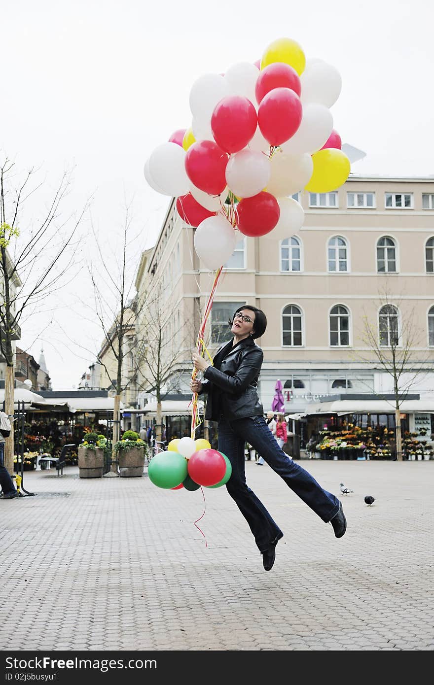 Happy young woman holding lots of ballons and try to fly. Happy young woman holding lots of ballons and try to fly