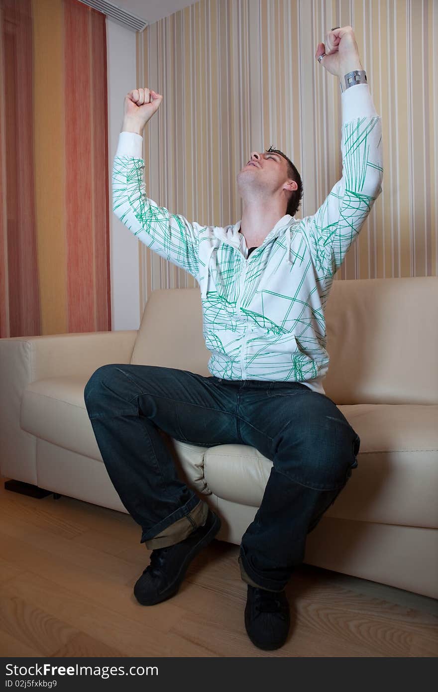 Guy sitting on the couch in the living room and watching interesting ball game on TV