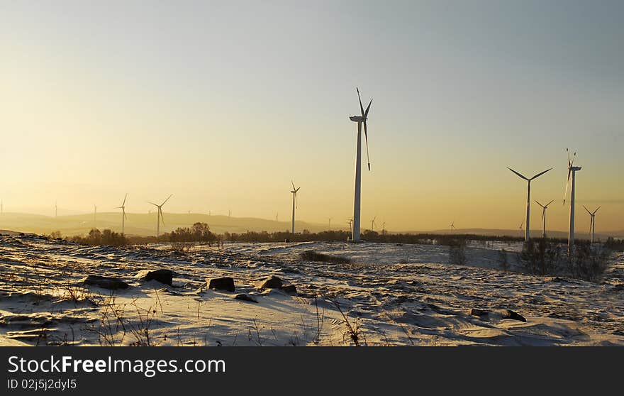 Wind power generator against dramatic sunrise or sunset in snow field. Wind power generator against dramatic sunrise or sunset in snow field