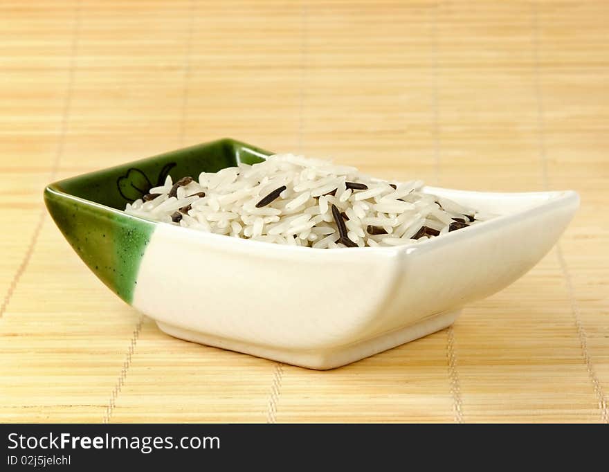 A bowl of mixed rice on a bamboo mat. A bowl of mixed rice on a bamboo mat