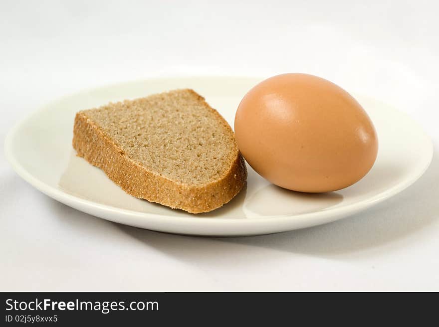 The bread and egg at white plate close-up on a white background. The bread and egg at white plate close-up on a white background