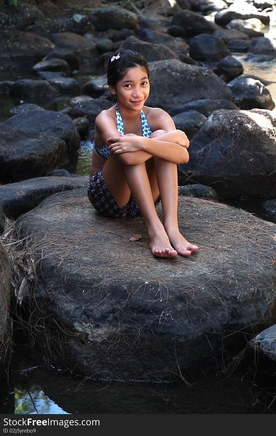 Young asian lady sitting in a rock by the river. Young asian lady sitting in a rock by the river