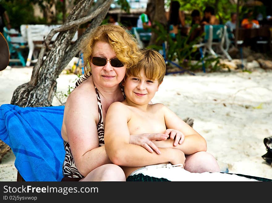 Mother is spooning with her happy smiling son at the beautiful beach