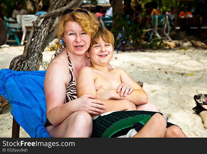 Mother is spooning with her happy smiling son at the beautiful beach