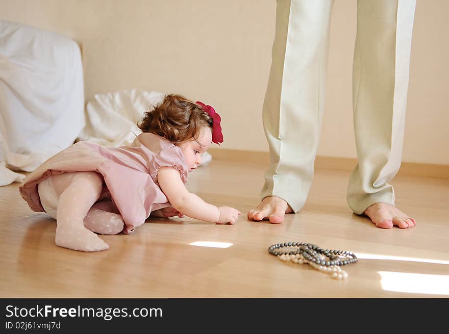 Cute baby girl lies on a floor and plays with feet of the daddy. Cute baby girl lies on a floor and plays with feet of the daddy