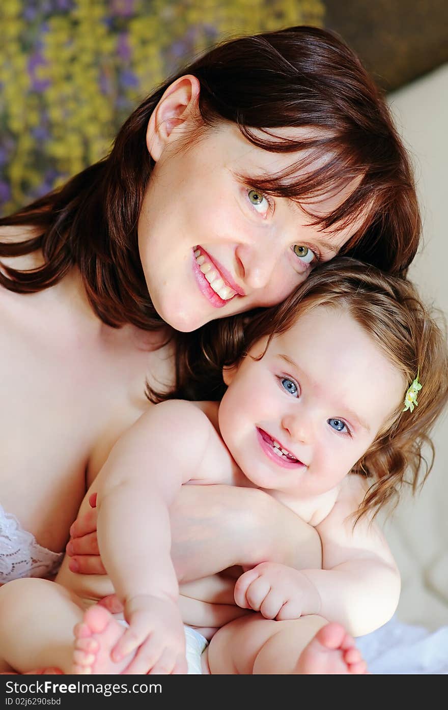 Closeup beautiful mother smiles and embraces her happy baby daughter. Closeup beautiful mother smiles and embraces her happy baby daughter