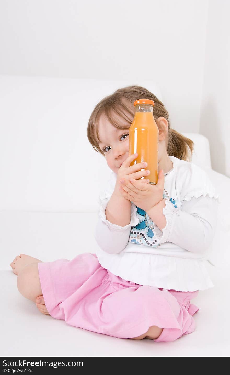 Sweet happy little girl on sofa with juice. Sweet happy little girl on sofa with juice