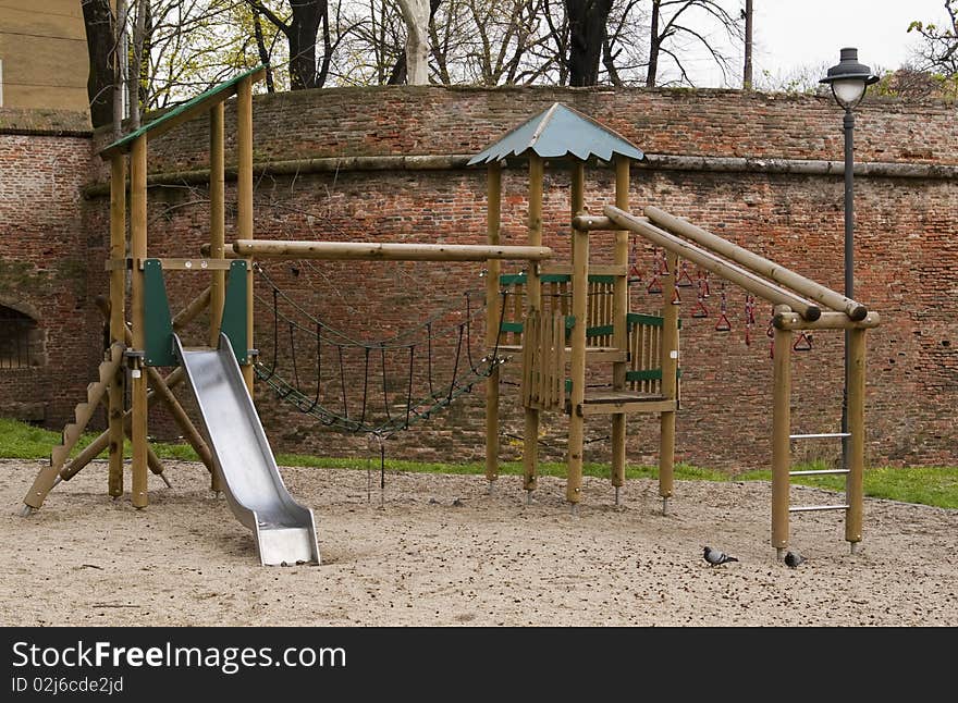 Wooden playground park with slide by old town walls