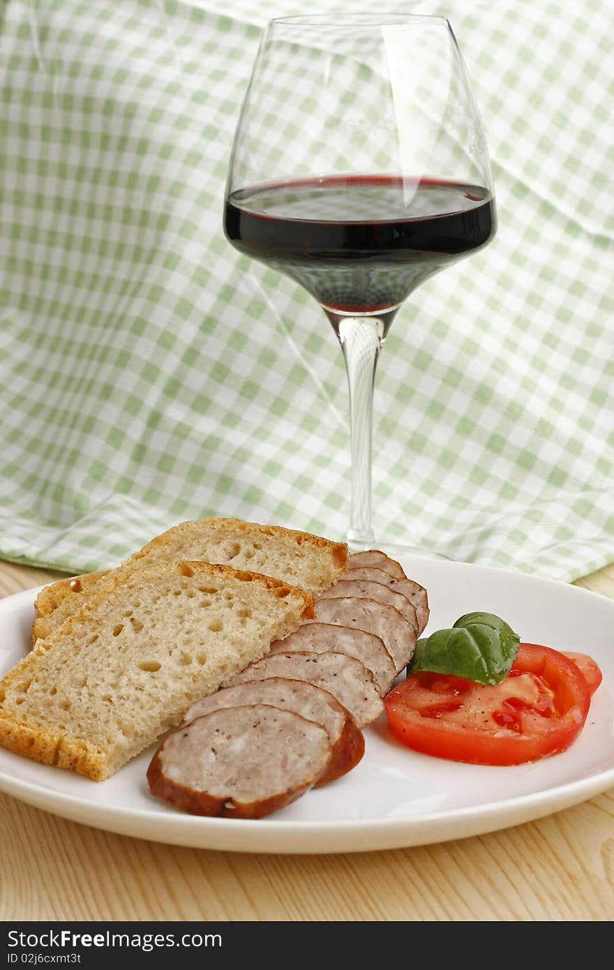 Traditional polish sausage with tomato, bread and glass of red wine. Traditional polish sausage with tomato, bread and glass of red wine