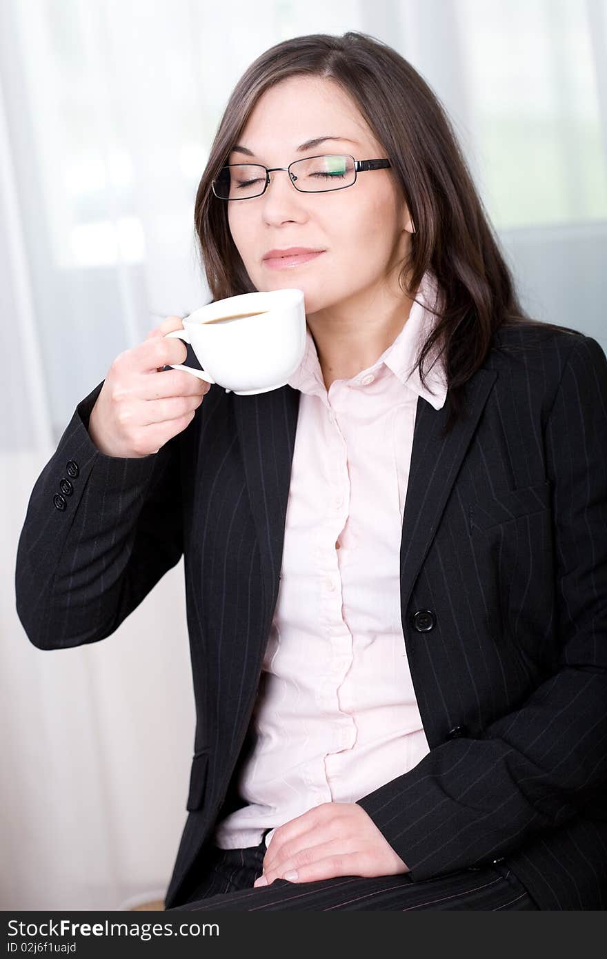 Young brunette businesswoman tasting coffee