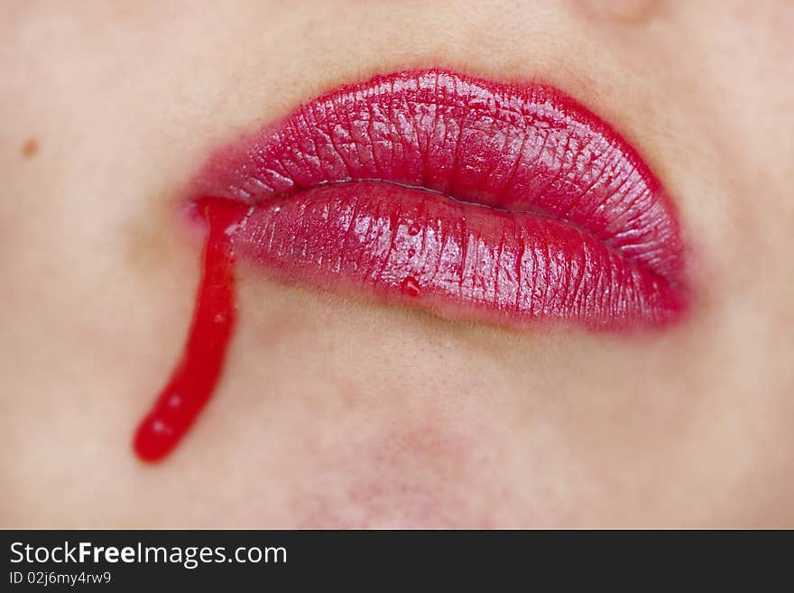 Close up view of some strawberry syrup on red lips. Close up view of some strawberry syrup on red lips.